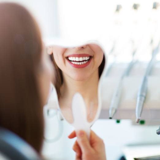 Woman looking at flawless smile after cosmetic dentistry