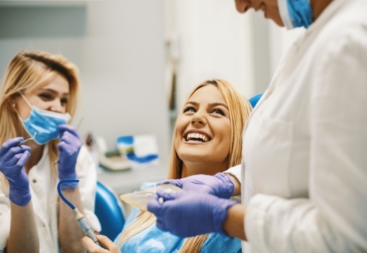 Dental patient laughing with dentist and dentistry team member