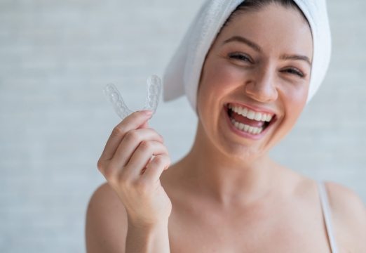 Woman holding clear nightguard for teeth grinding