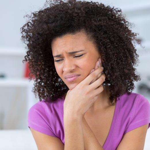 Woman in need of emergency dentistry holding cheek in pain