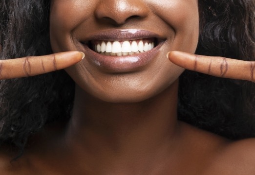 Woman pointing to smile after gum disease treatment