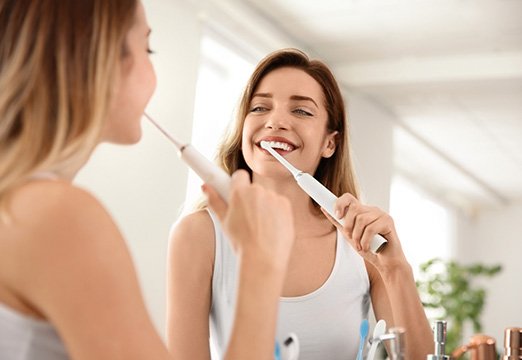Woman brushing dental implants in Glenmont