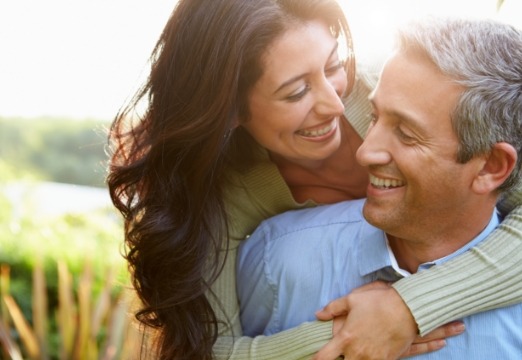 Man and woman smiling other after tooth replacement with dental implants