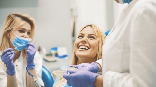 Dentist dental team member and patient laughing together