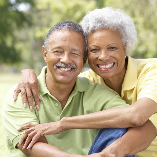 Man and woman smiling after replacing missing teeth