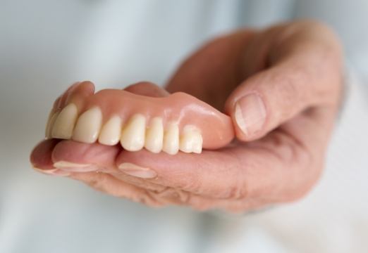 Person holding a full denture